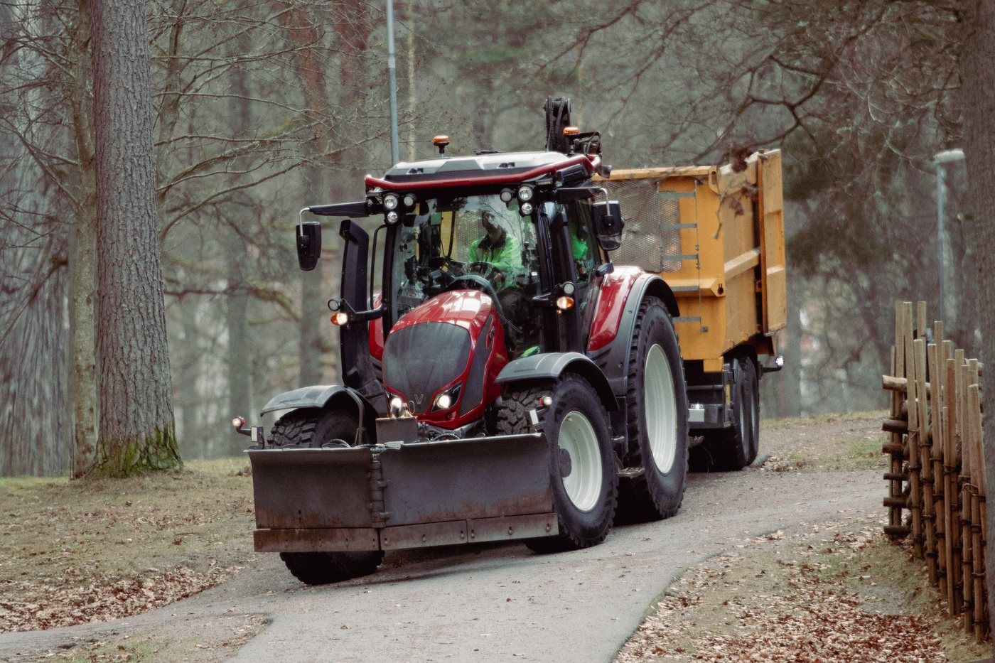 Traktor med släp på en grusväg genom tallskog