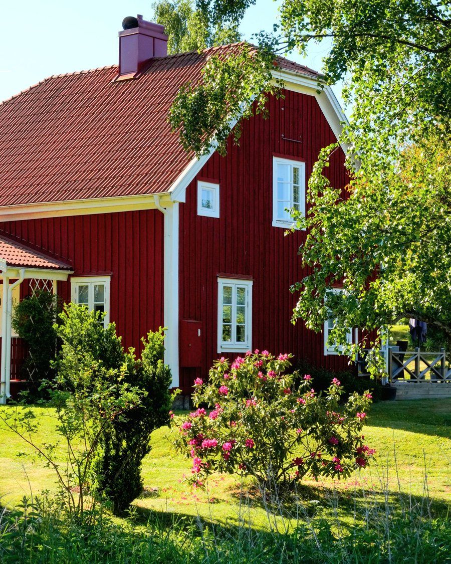 Rödmålad villa med vita knutar och grönskande trädgård